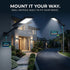 Two solar-powered outdoor LED light fixtures shown installed on a house exterior and a driveway at night, with text reading 'MOUNT IT YOUR WAY. WALL OR POLE.